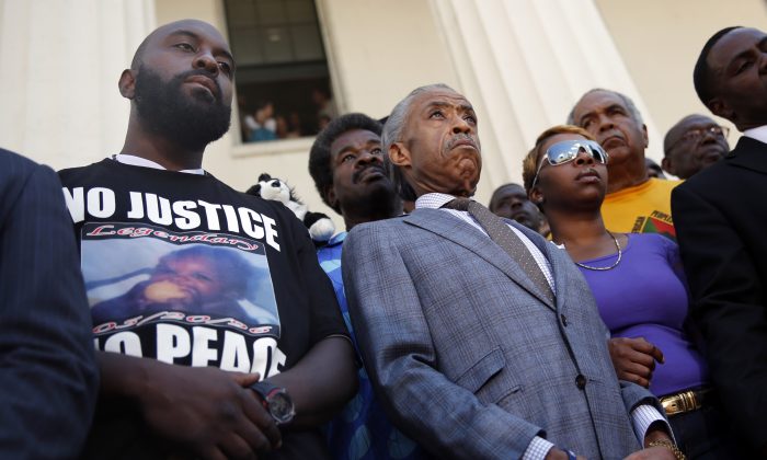 In this Aug. 12, 2014, photo civil rights leader Rev. Al Sharpton (C) stands with the parents of Michael Brown, Lesley McSpadden (R) and Michael Brown Sr. (L) during a news conference outside the Old Courthouse in St. Louis. Lingering questions about Michael Brown could be answered Wednesday as two news organizations seek the release of any possible juvenile records for the unarmed 18-year-old who was shot by a police officer last month. (AP Photo/Jeff Roberson)