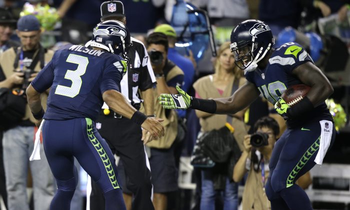 Seattle Seahawks quarterback Russell Wilson, left, celebrates with Derrick Coleman, right, after Coleman scored a touchdown in the second half of an NFL football game against the Green Bay Packers, Thursday, Sept. 4, 2014, in Seattle. (AP Photo/Stephen Brashear)