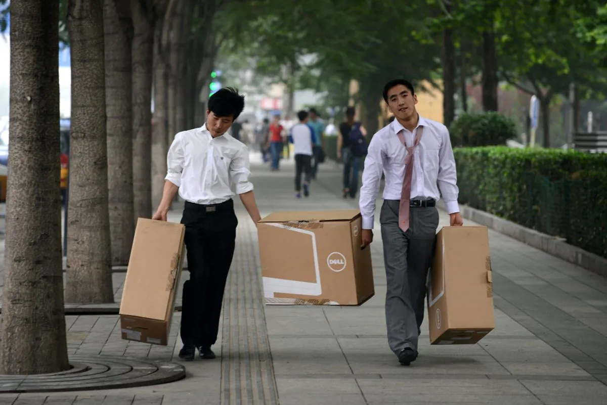 Two Chinese men carry goods along a street in Beijing on June 25, 2013. Peking University published a survey recently stating that the average starting salary for new college graduates in 2014 is only 2,400 yuan ($400), and 40 percent of recent graduates rely on their parents' financial support. (Wang Zhao/AFP/Getty Images)