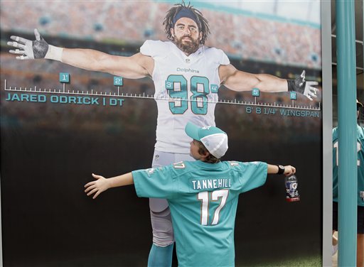 Football fan Samuel Hash, 11, of Lakeland, Fla., compares his size with Miami Dolphins defensive tackle Jared Odrick on a display board before an NFL football game between the Miami Dolphins and New England Patriots, Sunday, Sept. 7, 2014, in Miami Gardens, Fla. (AP Photo/Lynne Sladky)