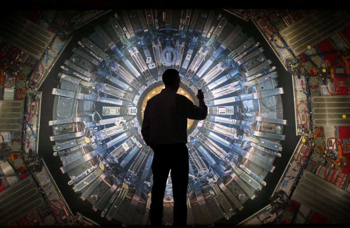 A visitor takes a phone photograph of a large back lit image of the Large Hadron Collider (LHC) at the Science Museum's 'Collider' exhibition in London, England, on Nov. 12, 2013. (Peter Macdiarmid/Getty Images)