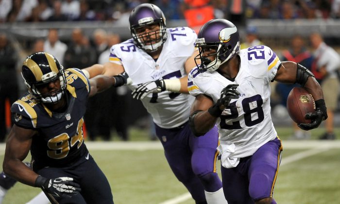 Minnesota Vikings running back Adrian Peterson, right, gets a block from offensive tackle Matt Kalil as St. Louis Rams defensive end Robert Quinn, left, gives chase during the third quarter an NFL football game Sunday, Sept. 7, 2014, in St. Louis. (AP Photo/L.G. Patterson)