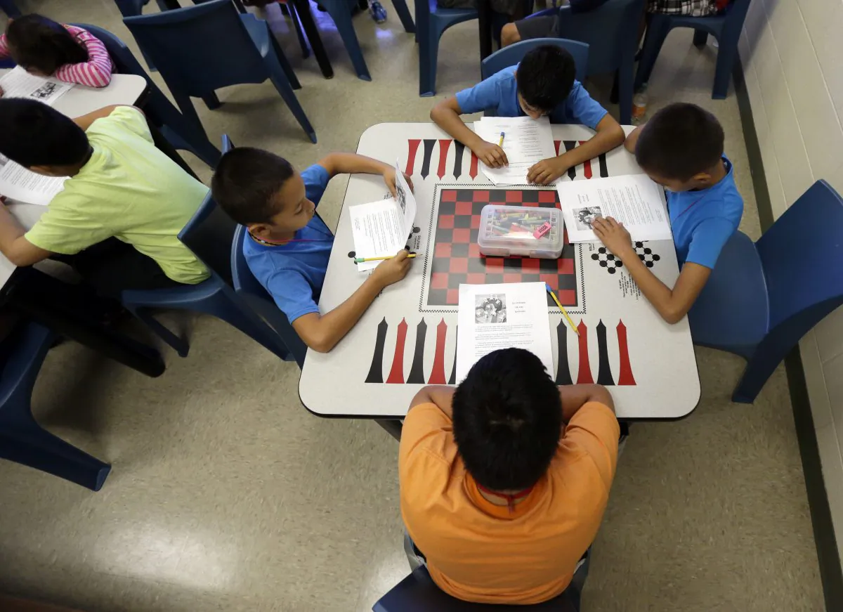A short story in Spanish is used in a class at the Karnes County Residential Center, a temporary home for immigrant women and children detained at the border, in Karnes City, Texas, Sept. 10, 2014. Unaccompanied minors who reach New York are being met by representatives who help the children register for school and other services. (AP Photo/Eric Gay)