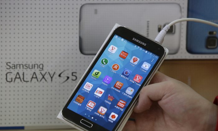 In this March 27, 2014 file photo, an employee shows Samsung's Galaxy S5 smartphone at a mobile phone shop in Seoul, South Korea; the Android 4.4.4 KitKat update is being rolled out to the phone. (AP Photo/Lee Jin-man, File)