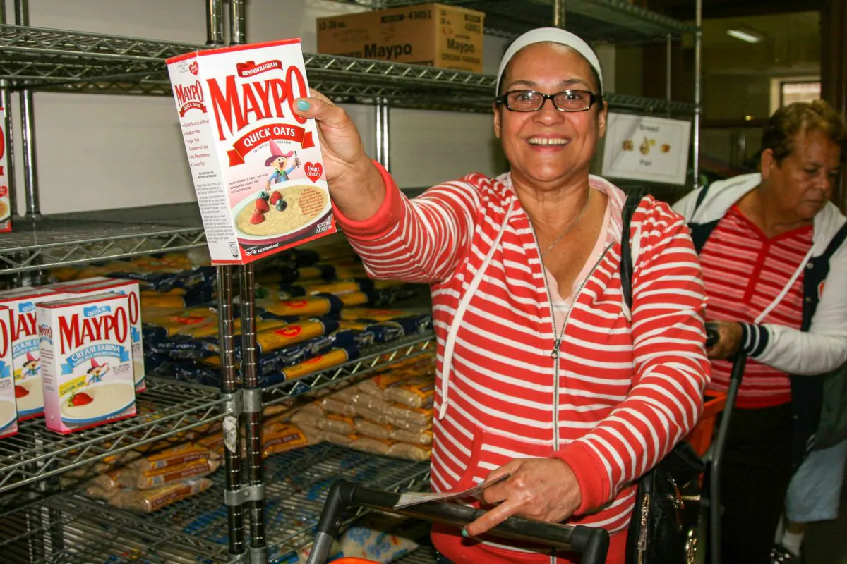 A customer holding up produce at West Side Campaign Against Hunger food bank in the Upper West Side on Monday, Sept. 18, 2014. (Shannon Liao/Epoch Times)