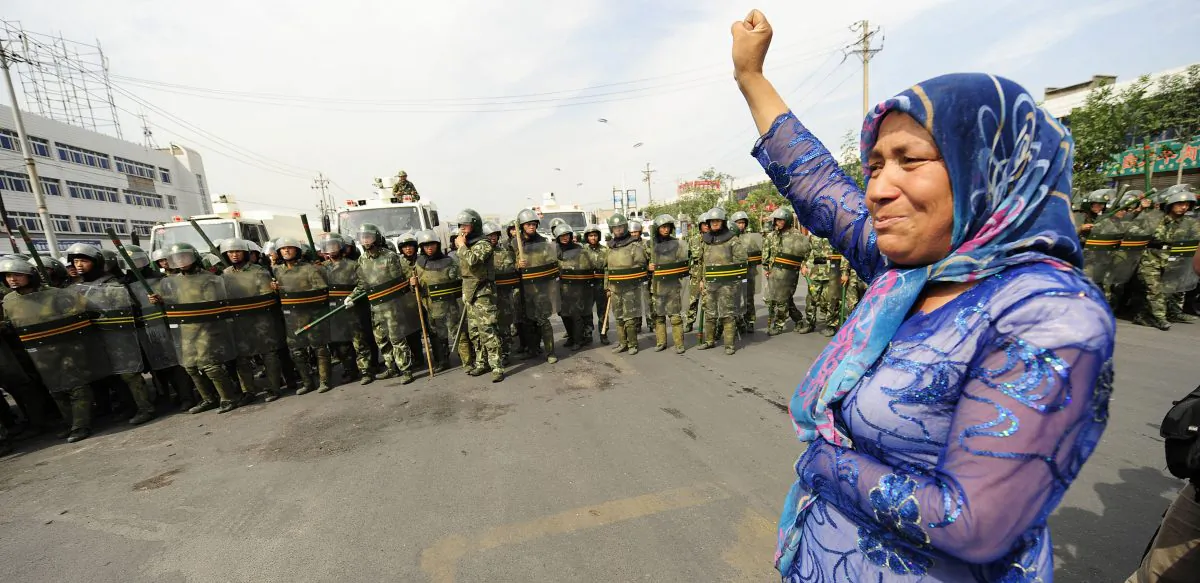 In this file photo, Chinese riot police watch a Muslim ethnic Uighur woman protest in Urumqi in China's far west Xinjiang province on July 7, 2009. (Peter Parks/AFP/Getty Images)