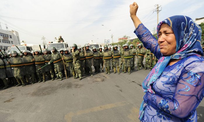 Chinese riot police watch a Muslim ethnic Uighur woman protest in Urumqi in China's far west Xinjiang province on July 7, 2009. On Sept. 21, 2014, coordinated explosions at Luntai County, Xinjiang killed at least two people. (Peter Parks/AFP/Getty Images)