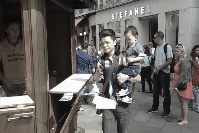 The man swipes flyers off the table of a Falun Gong information booth in Venice, Italy, on Sept. 22, 2014. (Lorenzo Terenzani)