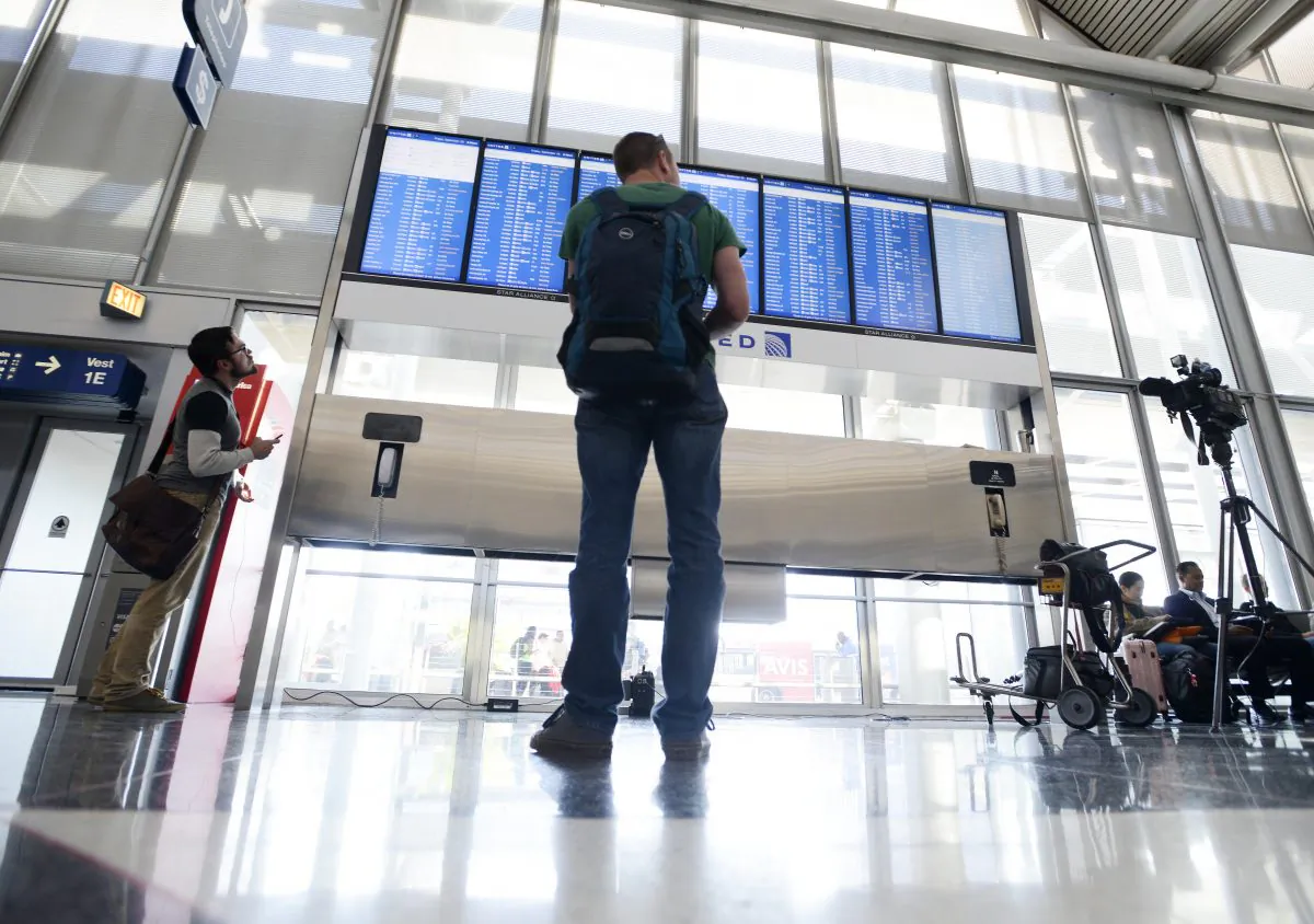 Dennis McCormack of Rockaway, N.J. checks the departure board only to find out that his flight to Newark, N.J. has been canceled at O'Hare International Airport in Chicago, Friday, Sept. 26, 2014. (AP Photo/Paul Beaty)