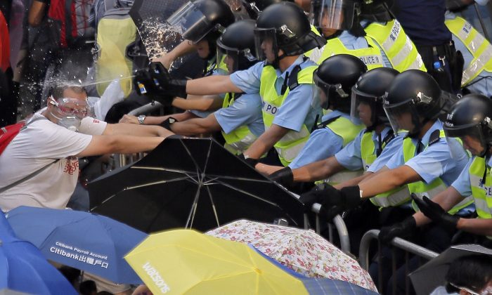 Riot police use pepper spray against protesters after thousands of people blocked a main road to the financial central district outside the government headquarters in Hong Kong, Sept. 28, 2014. (AP Photo/Vincent Yu, File)