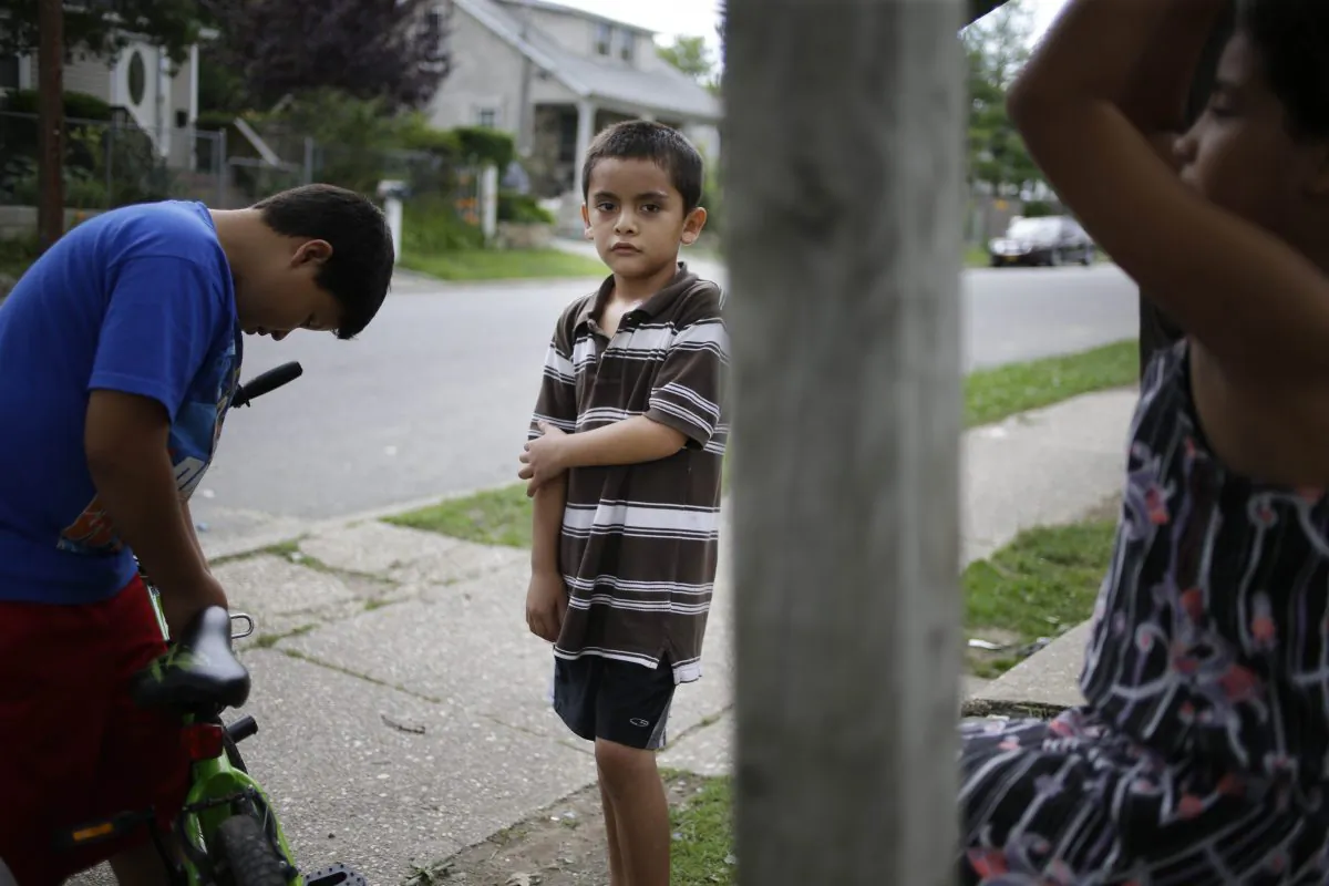 Kevin Torres, 7, plays with neighbors in the front yard of his apartment building in Huntington Station, N.Y., on July 17, 2014. Torres arrived in the United States, unaccompanied, from El Salvador in May 2014. The New York City Council is concerned that unaccompanied children scheduled to appear in immigration court are going to be left without legal representation. (AP Photo/Seth Wenig)