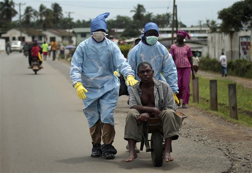 Residents of the St. Paul Bridge neighborhood wearing personal protective equipment take a man suspected of carrying the Ebola virus to the Island Clinic in Monrovia, Liberia, Sept. 28, 2014. (AP Photo/Jerome Delay)