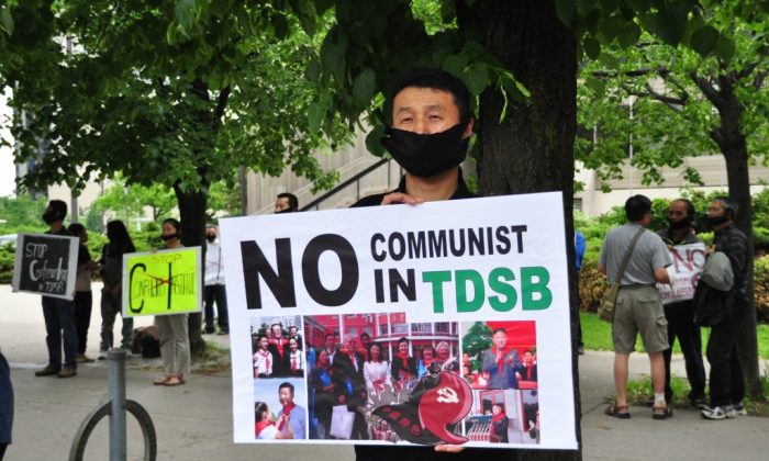 A demonstrator holds a sign to protest the Toronto District School Board's partnership with the Confucius Institute outside of the TDSB on June 11, 2014. (Allen Zhou/Epoch Times)