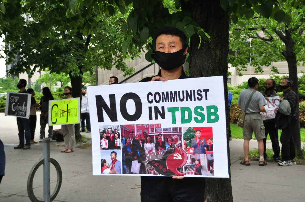 A demonstrator holds a sign to protest the Toronto District School Board's partnership with the Confucius Institute outside of the TDSB on June 11, 2014. (Allen Zhou/Epoch Times)
