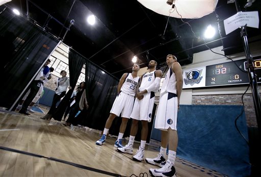 Dallas Mavericks forward Chandler Parsons (25), center Tyson Chandler (6) and forward Dirk Nowitzki (41) pose for a photographer as their handlers look on at left during NBA basketball media day in Dallas, Monday, Sept. 29, 2014. (AP Photo/LM Otero)