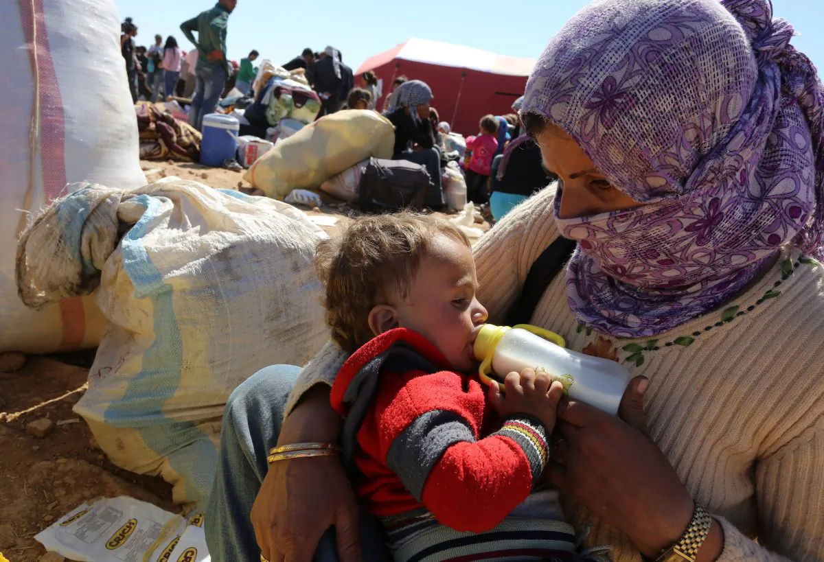 A mother feeds her baby as thousands of new Syrian refugees from Kobani arrive at the Turkey-Syria border  crossing of Yumurtalik near Suruc, Turkey, Wednesday, Oct. 1, 2014. (AP Photo/Burhan Ozbilici)