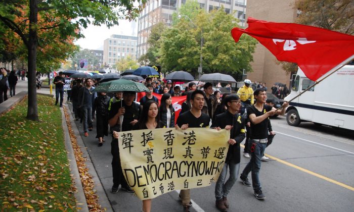 People carry umbrellas on a street in Toronto on Oct. 1, 2014 while demonstrating in solidarity with protesters in Hong Kong. Supporters of democracy took to Hong Kong's streets after the Chinese regime ruled that it would restrict who could run in the 2017 election for the island city's chief executive. (Ling Yi/Epoch Times)