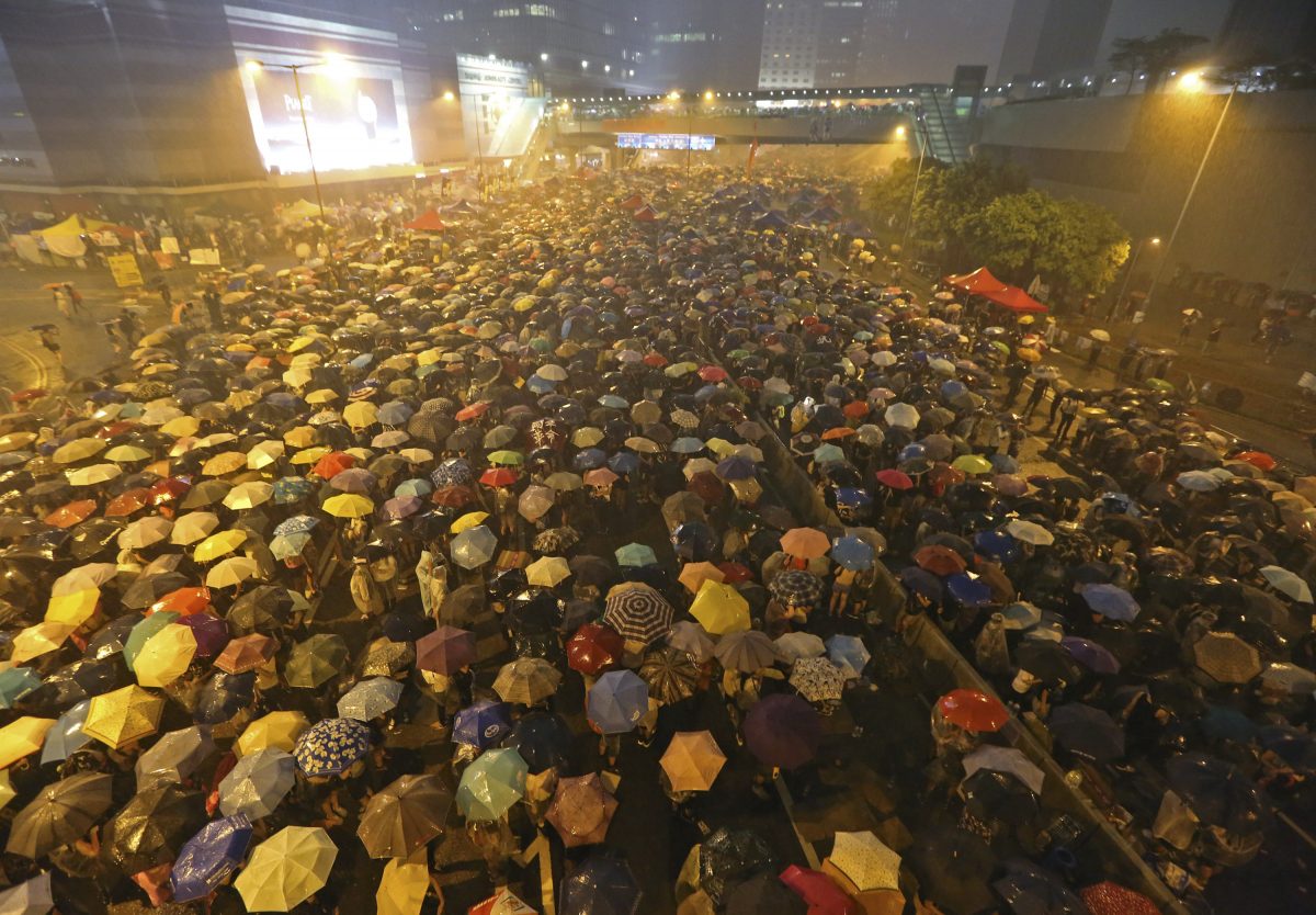 Pro-democracy protesters hold umbrellas under heavy rain in a main street near the government headquarters in Hong Kong late Tuesday, Sept. 30, 2014. The protesters demanded that Hong Kong's top leader meet with them on Tuesday and threatened wider actions if he did not, after he said China would not budge in its decision to limit voting reforms in the Asian financial hub. (AP Photo)