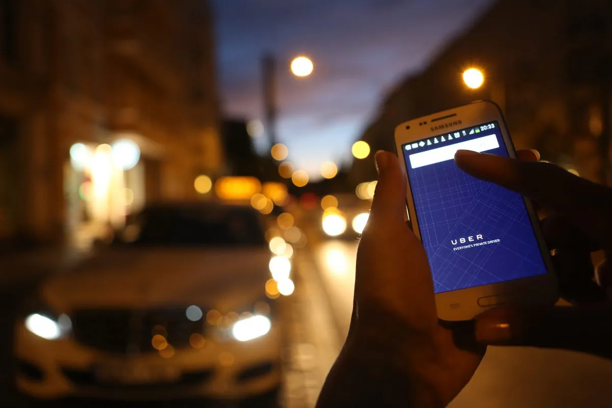 A woman uses the Uber app on an Samsung smartphone on Sept. 2, in Berlin, Germany. Uber, an app that allows passengers to buy rides from drivers who do not have taxi permits, uses a business model that has put it in conflict with the city of Ottawa, which is threatening $20,000 fines. (Adam Berry/Getty Images)