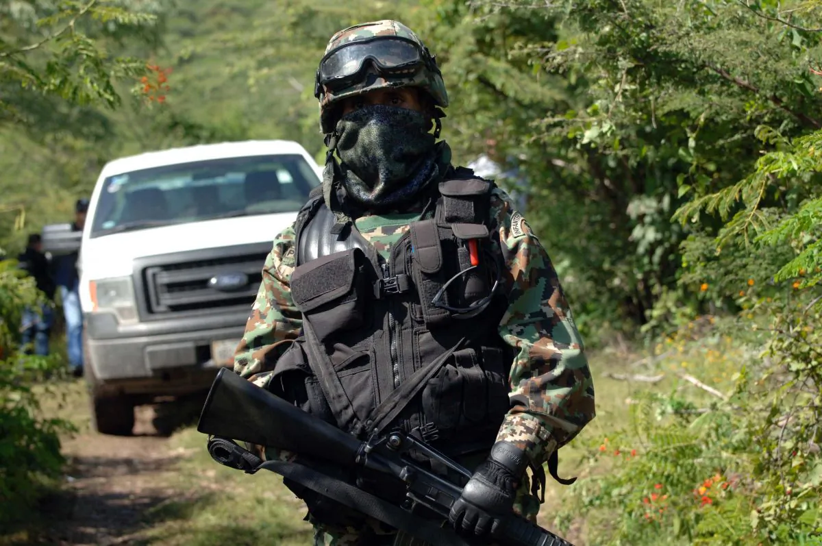 A Mexican navy marine guards the road that leads to the site where an alleged clandestine mass grave was found near the city of Iguala, Mexico, Saturday Oct. 4, 2014. (AP Photo/Alejandrino Gonzalez)
