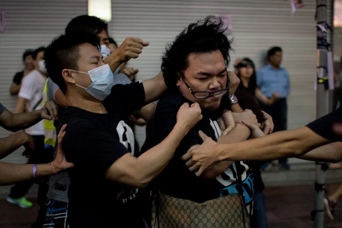 A group of men in masks beat up a man (R) who tried to stop them from removing barricades from a pro-democracy protest area in the Causeway Bay district of Hong Kong on Oct. 3, 2014. Sources say Hong Kong's chief executive Leung Chun-ying has employed mafia groups to harass the protesters. (Alex Ogle/AFP/Getty Images)