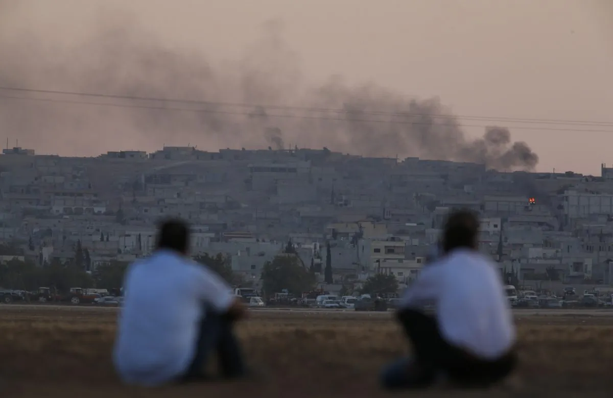 FILE - In this Oct. 7, 2014 file photo, Turkish Kurds sit on the outskirts of Suruc, on the Turkey-Syria border, as they watch smoke rising from a fire following an airstrike in Kobani, Syria, where the fighting between militants of the Islamic State group and Kurdish forces intensified. After two months, the U.S.-led aerial campaign in Iraq has so far hardly dented the core of the Islamic State group’s territory. The extremists’ grip on major cities across Iraq and neighboring Syria remains unquestioned. The campaign has brought some gains, with Kurdish fighters taking back towns on the fringes of the Islamic State group’s territory. But those successes only underline a major weakness: Besides the Iraqi Kurds, there are no forces on the ground ready to capitalize on the airstrikes. (AP Photo/Lefteris Pitarakis)