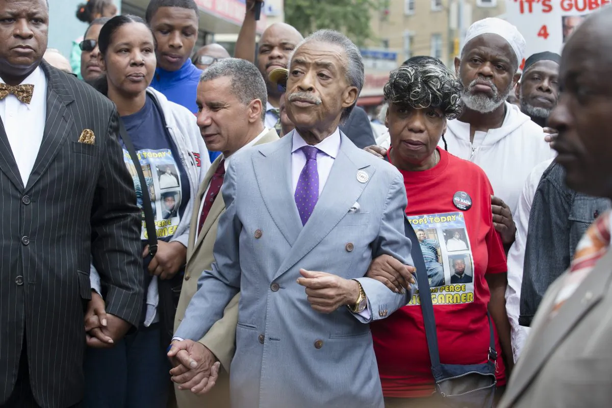 The Rev. Al Sharpton (C) holds hands with former New York Gov. David Paterson (L) and Gwen Carr (R), mother of Eric Garner, as they arrive before a march to protest the death of 43-year-old Eric Garner in the Staten Island borough of New York on Aug. 23, 2014. The Garner family has filed a notice of claim to sue New York City, the Police Department, and six individual police officers for $75 million. (AP Photo/John Minchillo)