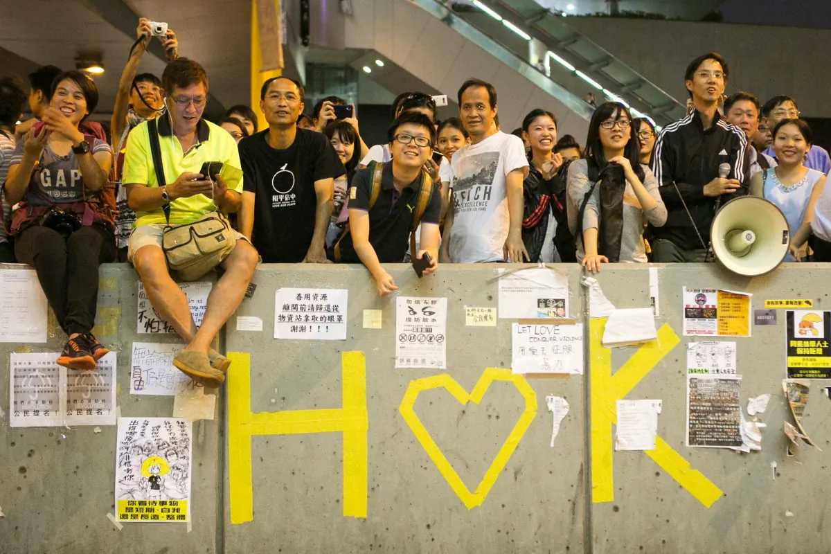 Pro-democracy protesters smile as they listen to a man lead the group into a song in the Central District of Hong Kong on Oct. 7, 2014. (Benjamin Chasteen/Epoch Times)