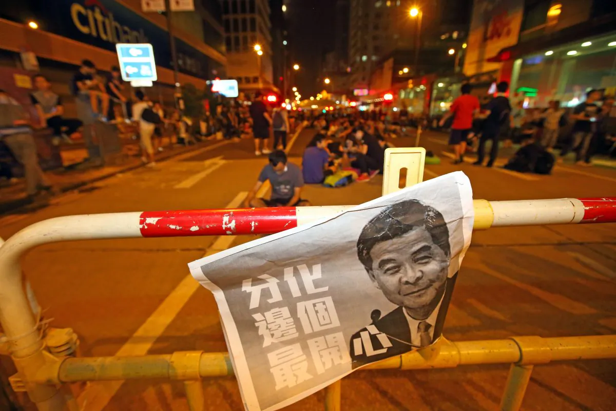 A poster with Leung Chun-ying’s portrait next to Chinese characters that read “Polarization, who is the happiest?” After the protesters in Mong Kok were assaulted, protesting students and citizens were asked to leave for safety reasons, but some still remained on Oct 4, 2014. (Poon/Epoch Times)