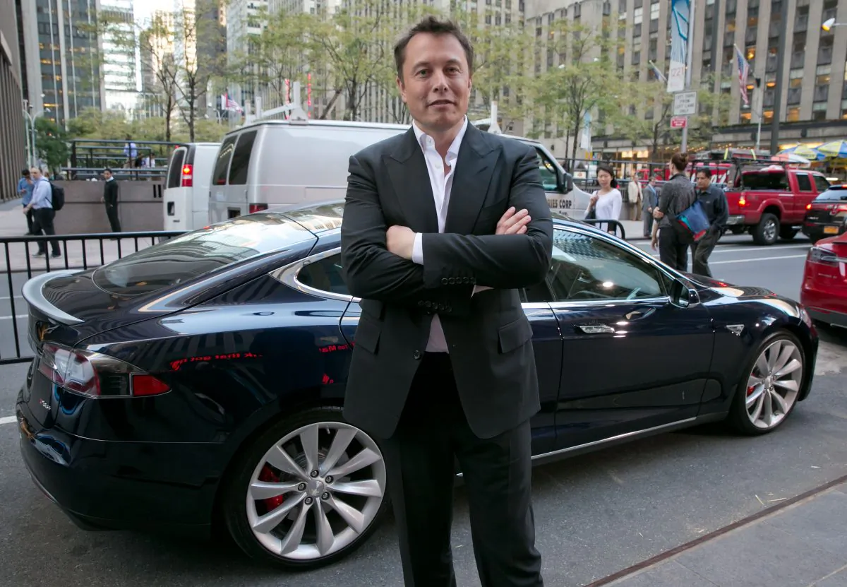 SpaceX billionaire founder and chief executive, and Tesla Motors CEO Elon Musk, poses beside a Tesla in New York on Sept. 17, 2014. (AP Photo/Richard Drew)