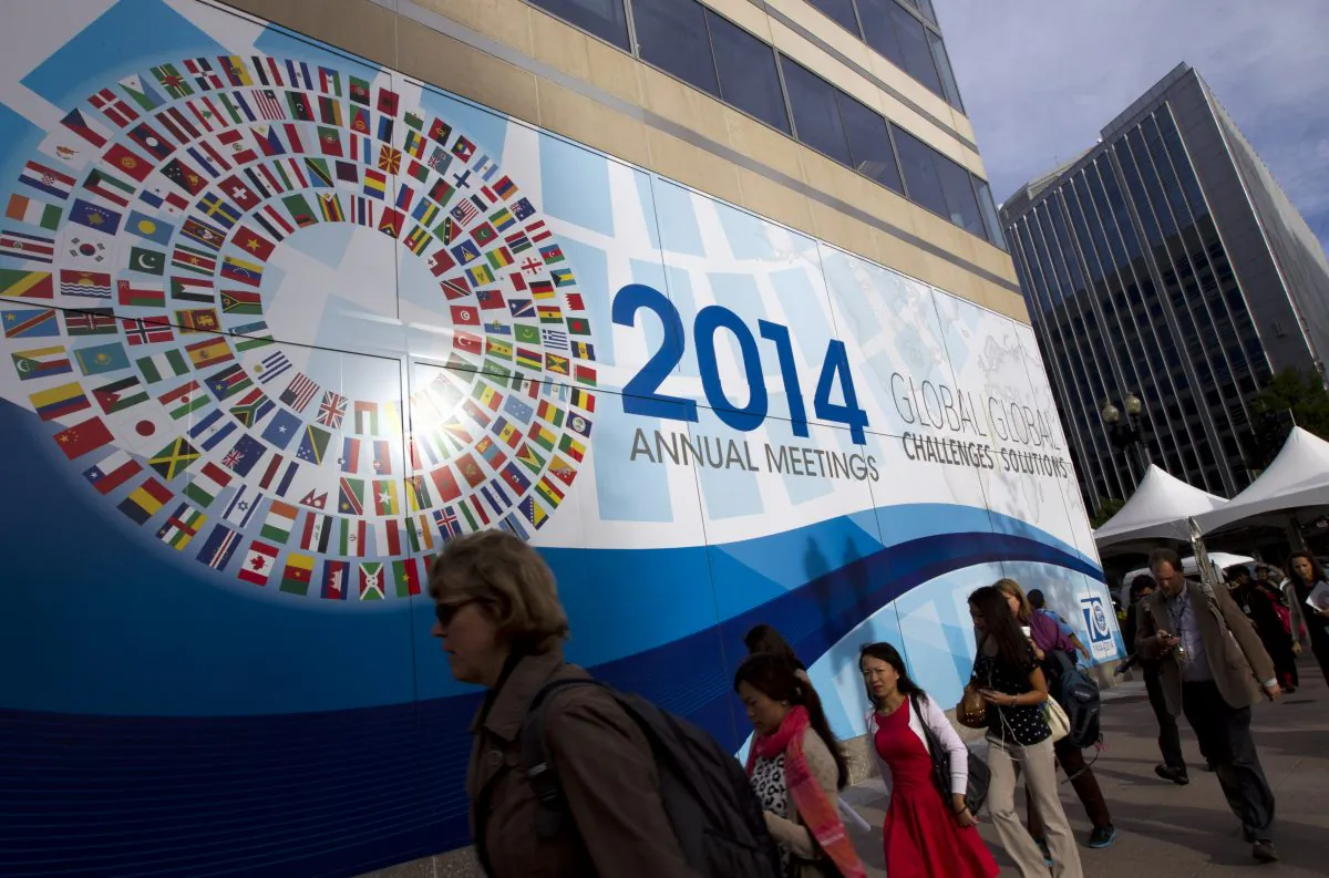 People walk past the International Monetary Fund (IMF) headquarters in Washington, Thursday, Oct. 9, 2014. The IMF, World Bank, finance ministers and central bank presidents of the Group of 20 nations will hold discussions on Oct. 10. Treasury Secretary Jacob Lew and Federal Reserve Chair Janet Yellen will represent the United States. (AP Photo/Jose Luis Magana)