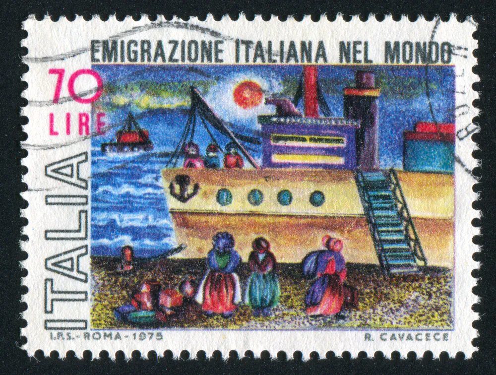 A stamp celebrating Italian emigration of the past century. The migration continues unabated, thanks to the economic downturn. 
‘Italian Emigration in the World’ says the stamp.(Shutterstock*) 