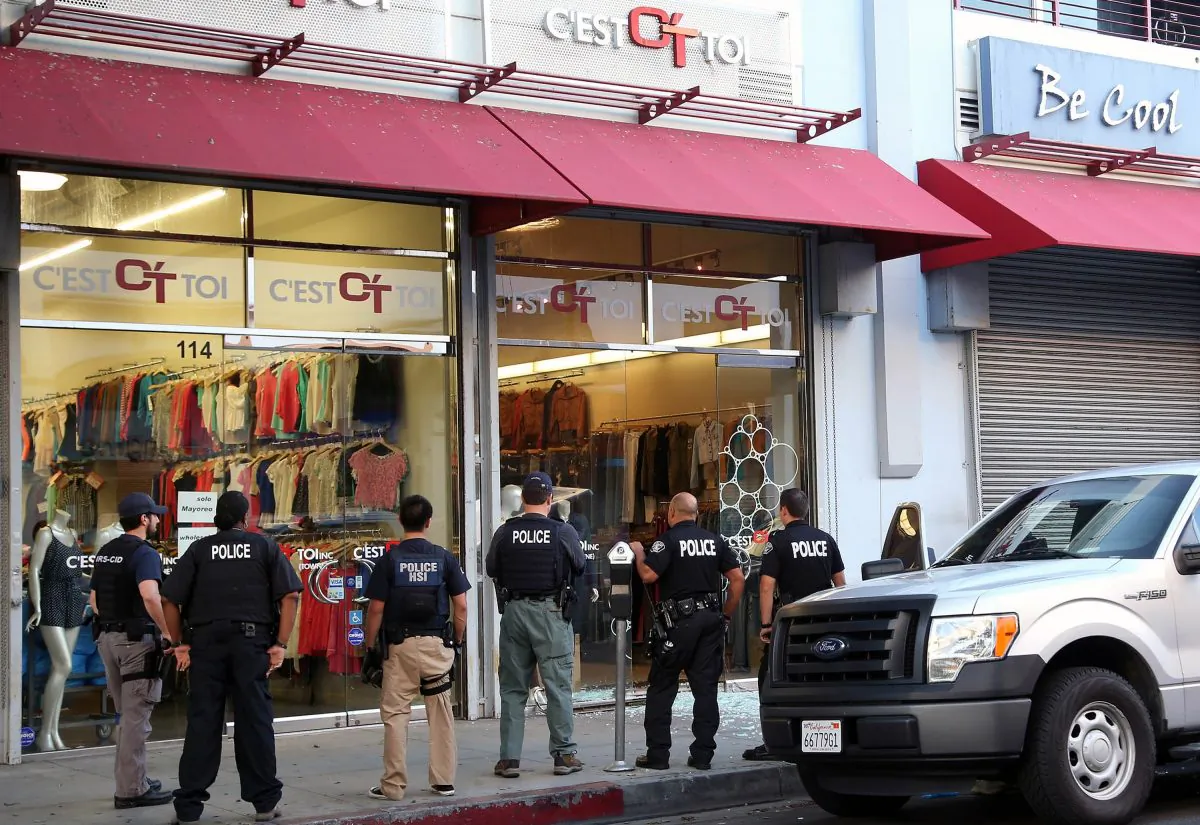 Law enforcement agents stand outside the C'est Toi Jeans clothing store after a raid in the Los Angeles Fashion District, on Sept. 10, 2014. (Nick Ut/AP Photo)