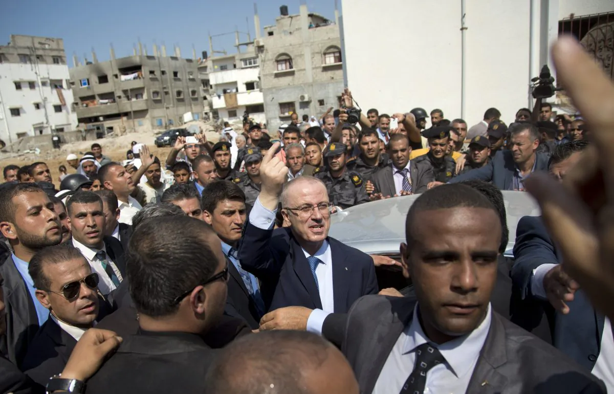 FILE - In this file photo taken Thursday, Oct. 9, 2014, Palestinian Prime Minister Rami Hamdallah, center, speaks to people during his visit to the Gaza's neighborhood of Shijaiyah. The wars between Israel and Hamas tend to be futile and frustrating for all. Each side ends up more or less where it began, having learned little, entrenched in its position, preparing for the next pointless, deadly round. (AP Photo/Khalil Hamra, File)