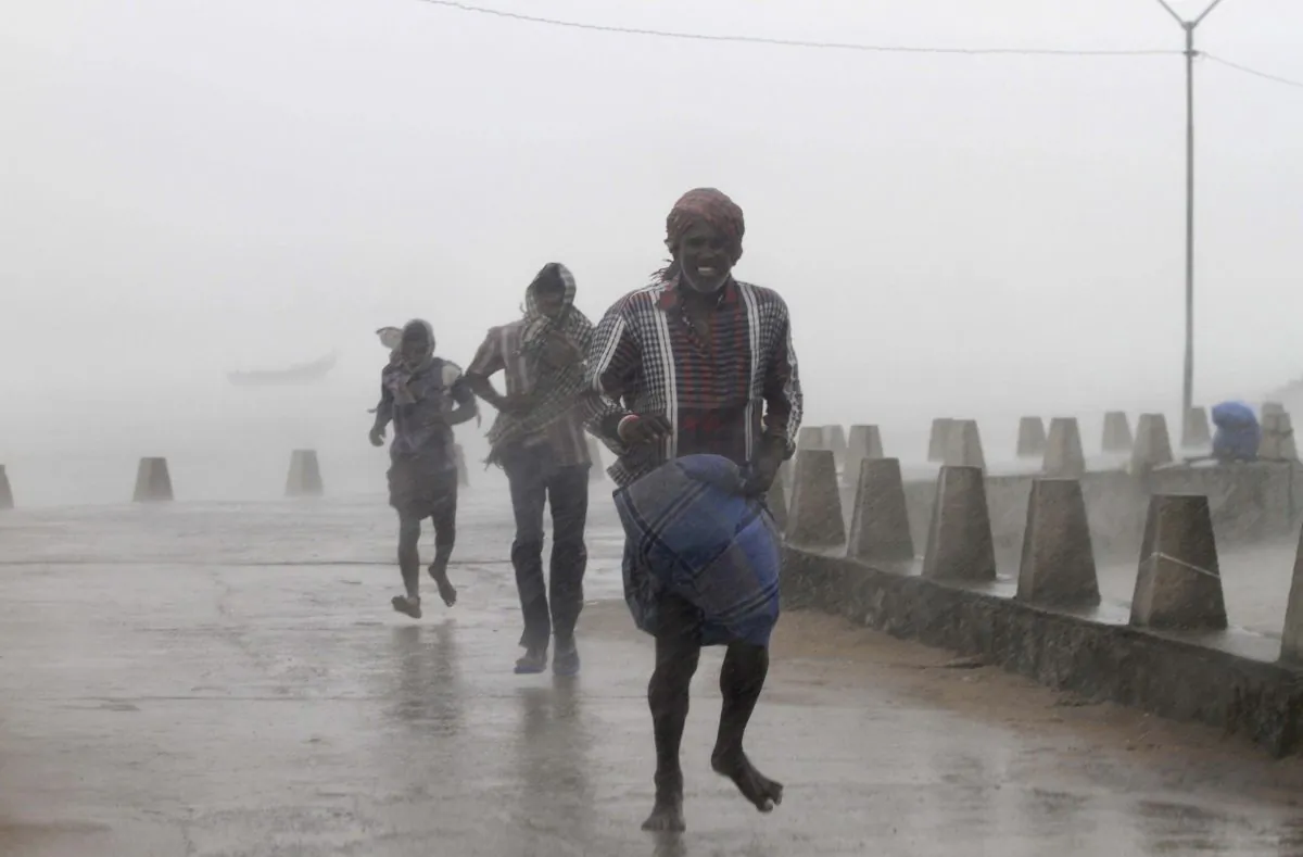 People run for shelter as heavy rain and wind gusts rip through the Bay of Bengal coast at Gopalpur, Orissa, about 285 kilometers (178 miles) north east of Visakhapatnam, India, Sunday, Oct. 12, 2014. Trees were uprooted and power cables snapped as a powerful cyclone swept through the Bay of Bengal and slammed into the southern city of Visakhapatnam, one of two storms pounding Asia on Sunday. (AP Photo/Biswaranjan Rout)