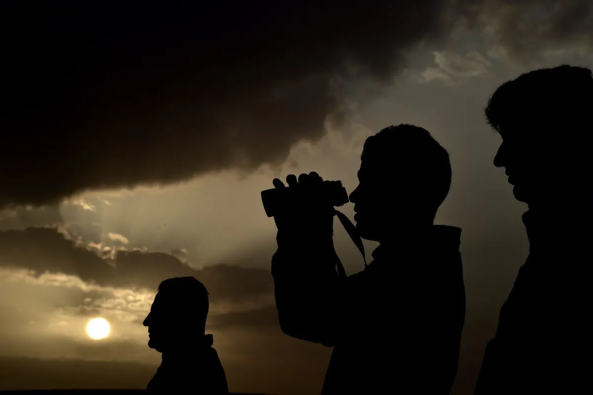 Kurdish people wach from atop a hill near the Turkish-Syrian border in the southeastern village of Mursitpinar, Sanliurfa province, the fighting in the Syrian town of Ain al-Arab, known as Kobani by the Kurds, on Oct. 12, 2014. UN chief Ban Ki-moon on Oct. 12 urged action to prevent a 'massacre' of civilians in the Syrian town Kobani, saying thousands of lives were at stake as jihadists battled Kurdish defenders. (Aris Messinis/AFP/Getty Images)