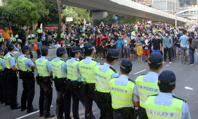 Police officers (front) and pro-democracy demonstrators face off near the government offices in Hong Kong on October 13, 2014. Dozens of Hong Kong police were massing at protest sites where pro-democracy demonstrators have been holding more than two weeks of rallies, paralysing parts of the Asian financial hub. (AFP PHOTO / Laurent FIEVET)