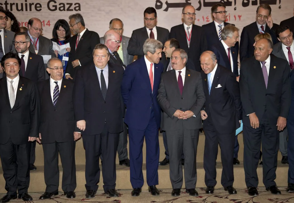 US Secretary of State John Kerry (front-C) talks with Jordanian Foreign Minister Nasser Judeh, to his right, as they gather for a group photo with other Gaza Donor Conference attendees in Cairo, Egypt, Sunday, Oct. 12, 2014. Kerry announced immediate US assistance of $212 million as the conference began. Qatar has pledged $1 billion and the United Arab Emirates pledged $200 million toward reconstruction of Gaza Strip after a 50-day Israel-Hamas war. Palestinian President Mahmoud Abbas has said Gaza needs $4 billion. (AP Photo/Carolyn Kaster)