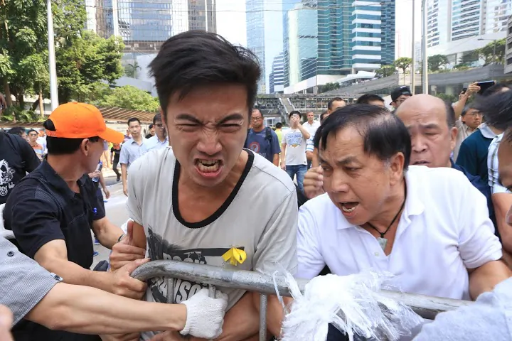 Opponents of the occupy movement in Hong Kong launch a coordinated attempt to remove barricades set up by student groups on Queensway, a major thoroughfare in the Central District on Oct. 13, 2014. The group, composed of dozens of men, cut ties holding barricades together and dragged them away. (Yu Kong/Epoch Times)