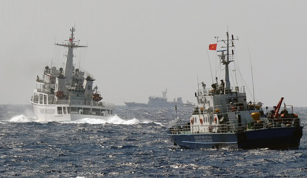 This picture taken from a Vietnam Coast Guard ship on May 14, 2014, shows a China Coast Guard ship (L) blocking the way of a Vietnam Coast Guard ship near to the site of a Chinese drilling oil rig (R, background) being installed at the disputed water in the South China Sea off Vietnam's central coast. (Hoang Dinh Nam/AFP/Getty Images)