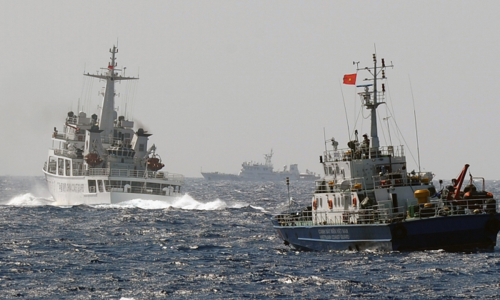This picture taken from a Vietnam Coast Guard ship on May 14, 2014, shows a China Coast Guard ship (L) blocking the way of a Vietnam Coast Guard ship near to the site of a Chinese drilling oil rig (R, background) being installed at the disputed water in the South China Sea off Vietnam's central coast. (Hoang Dinh Nam/AFP/Getty Images)