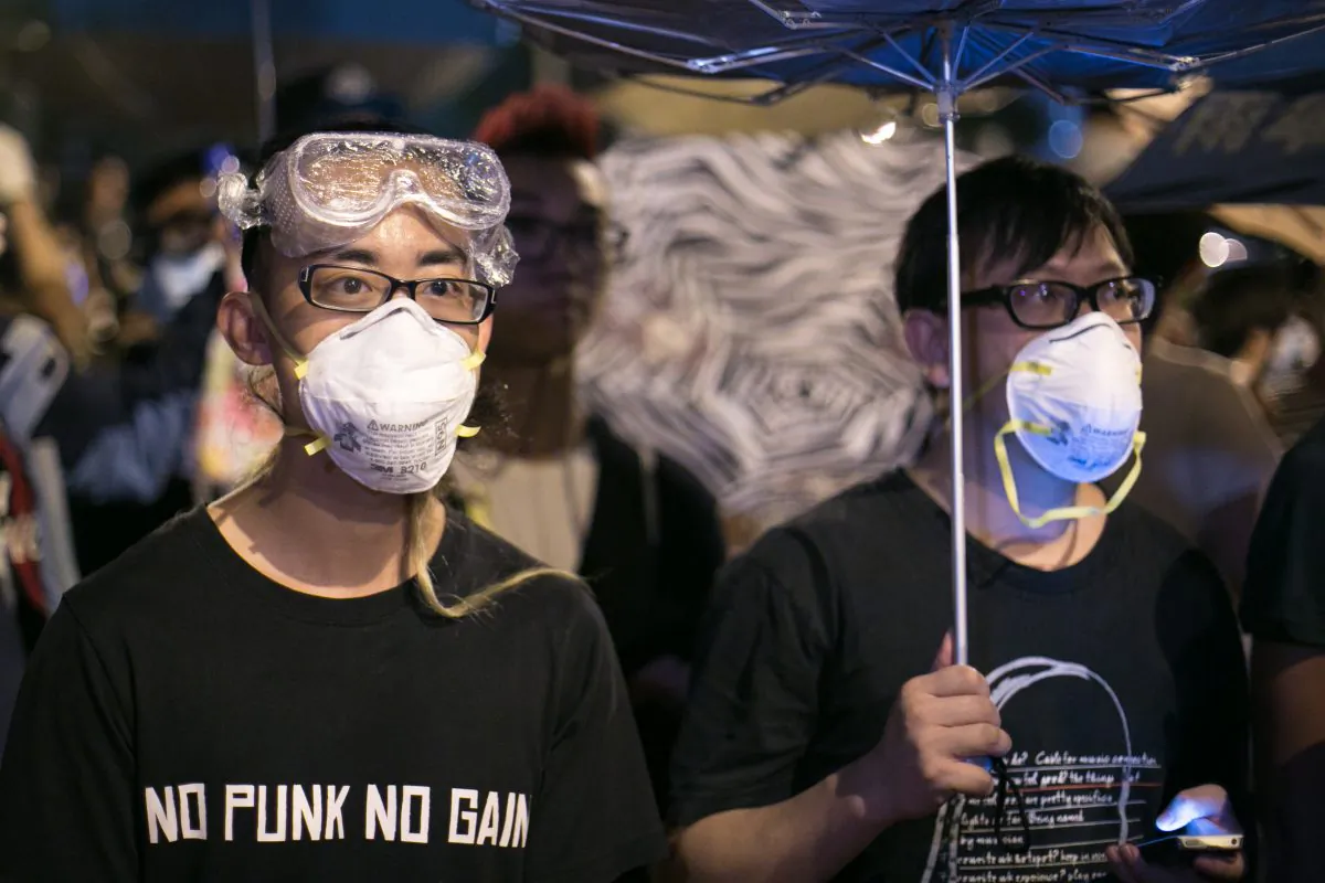 Pro-democracy protesters stand behind barricades as police stand guard on the other side on Lung Wo Road, one of the major roadways in Hong Kong, on Oct. 14, 2014. (Benjamin Chasteen/Epoch Times)
