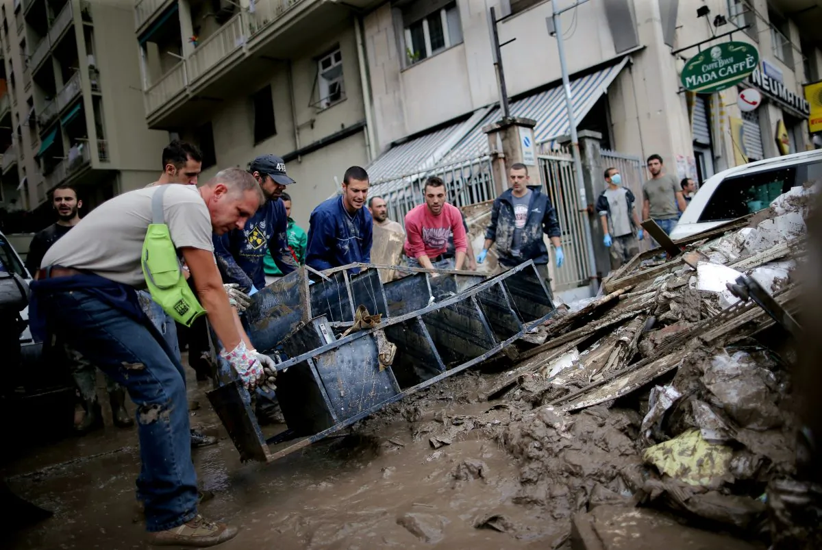 People carry garbage in downtown Genoa on Oct. 11, 2014, after one person died the day before, when flood waters swept through the city following unexpectedly heavy overnight rain, which caught officials unprepared despite similar deadly floods less than three years ago. One of Genoa's biggest rivers, the Bisagno, burst its banks shortly before midnight after days of heavy rain, sending torrents of muddy water through the streets of the medieval port city, smashing shop windows and sweeping aside cars. (Marco Bertorello/AFP/Getty Images)