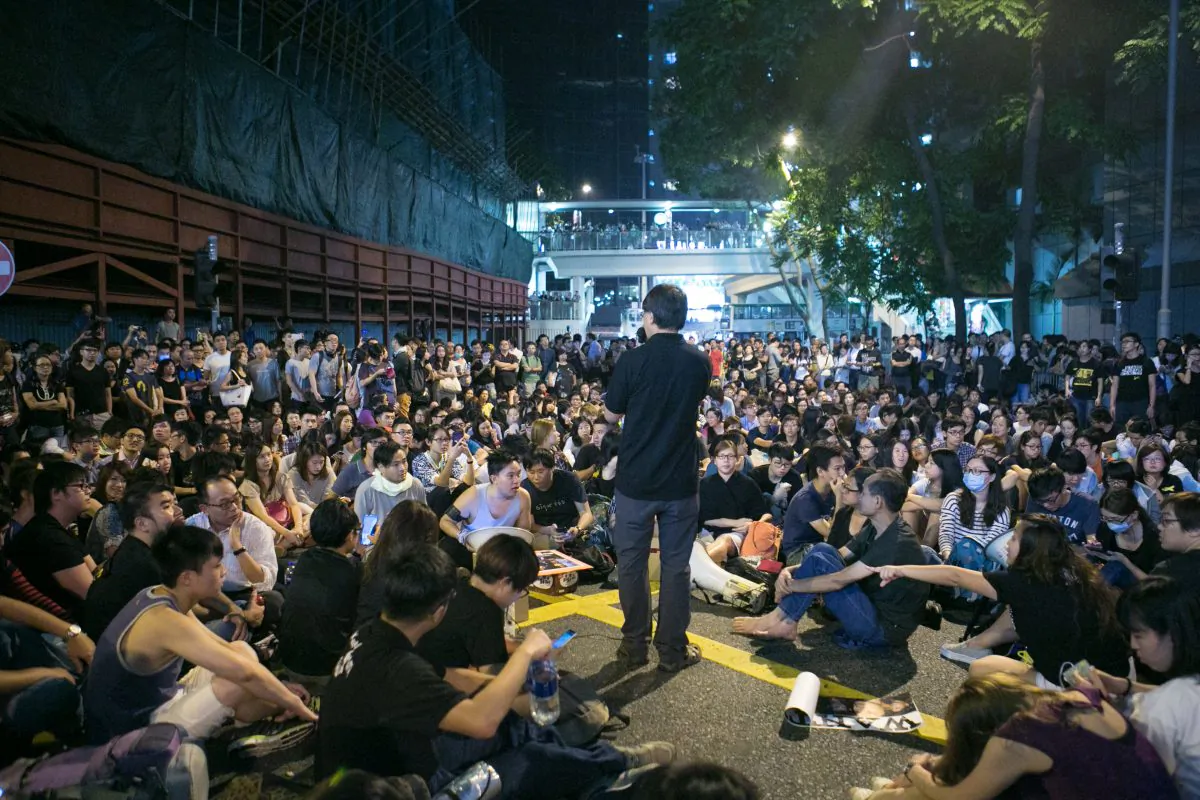 Pro-democracy protesters hold a rally in front of the Hong Kong police headquarters after an earlier incident where the police beat protesters with their fists and batons for taking over a major roadway on Oct. 15, 2014. (Benjamin Chasteen/Epoch Times)