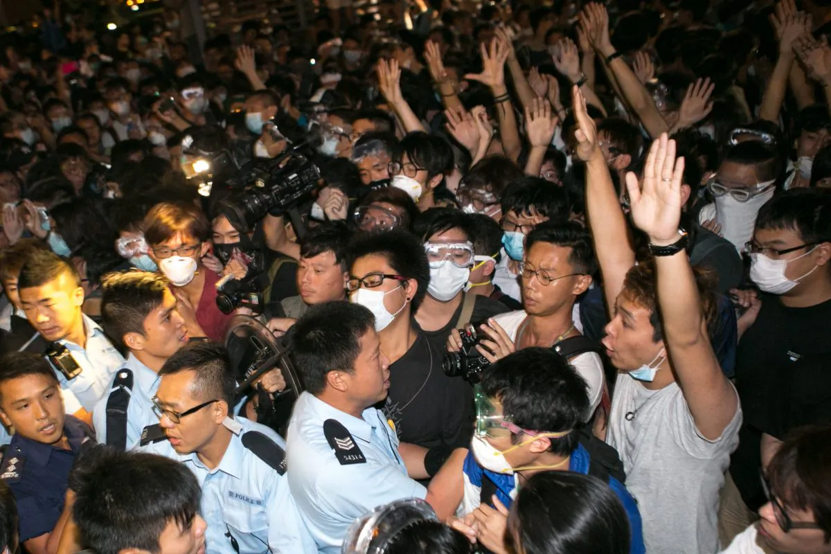 Pro-democracy protesters hold their hands up to show they are unarmed to police officers after they tried to shutdown Lung Wo Road for the second night in a row in Hong Kong on Oct. 16, 2014. (Benjamin Chasteen/Epoch Times)