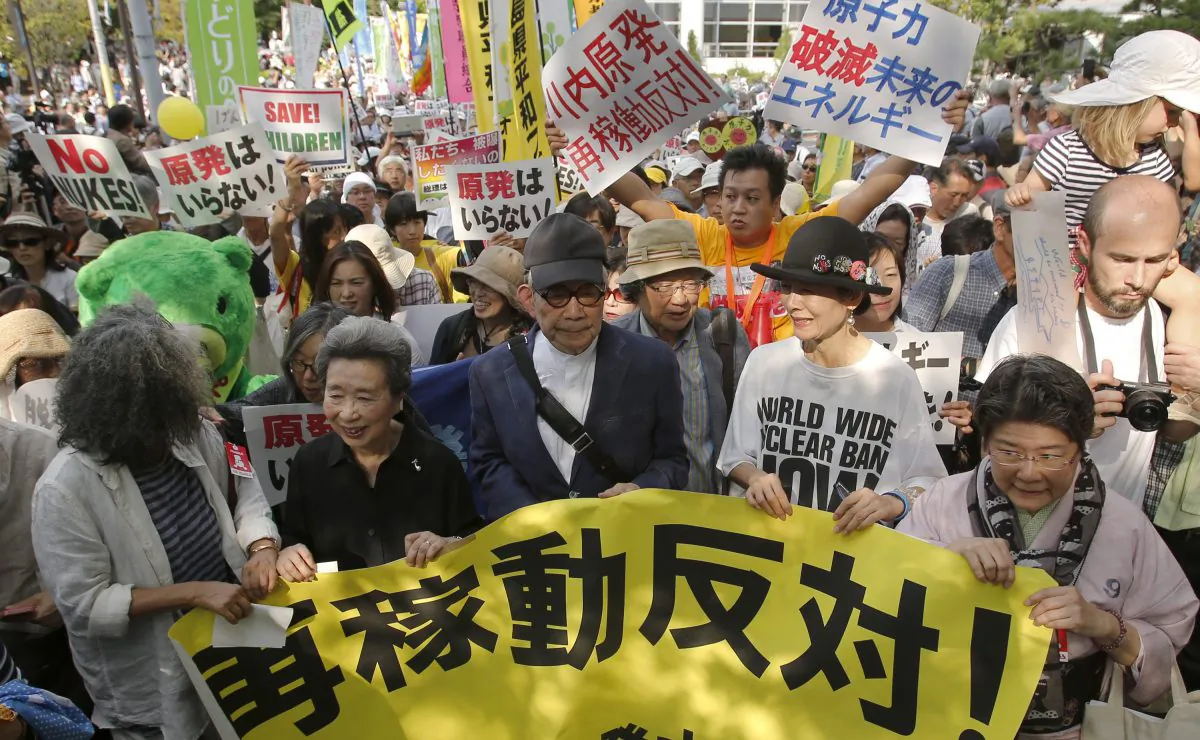 Nobel laureate Kenzaburo Oe (C) along with other participants march against Japanese nuclear power plant in Tokyo, Tuesday, Sept. 23, 2014. A nuclear power plant in southern Japan won regulators' approval this month under new safety standards imposed after the 2011 Fukushima disaster, a key step toward becoming the first to restart under the tighter rules. The word on a banner read: "Oppose to the resumption of (nuclear) operations!" (AP Photo/Shizuo Kambayashi)