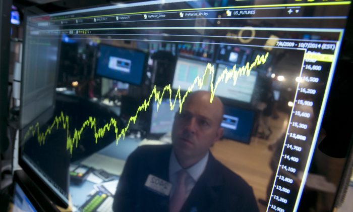 Specialist Jay Woods is reflected in a screen at his post that shows five years of the Dow Jones industrial average, on the floor of the New York Stock Exchange, on July 3, 2014. (AP Photo/Richard Drew)