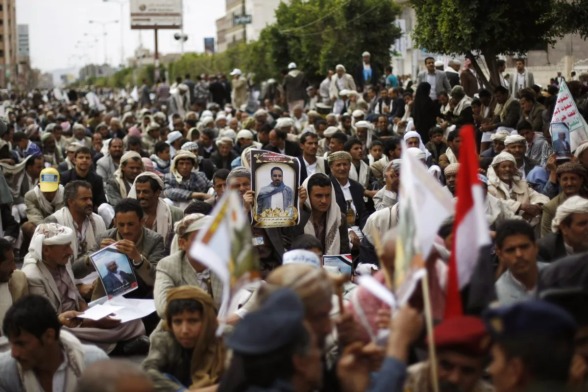 A mourner, center, holds a poster of a man who was killed Thursday by a suicide bomber in central Sanaa, Yemen, Tuesday, Oct. 14, 2014. Two suicide bombings in Yemen killed nearly 70 people last Thursday, with one targeting an anti-government rally by followers of the Houthi Shiite group, who control Sanaa. (AP Photo/Hani Mohammed)