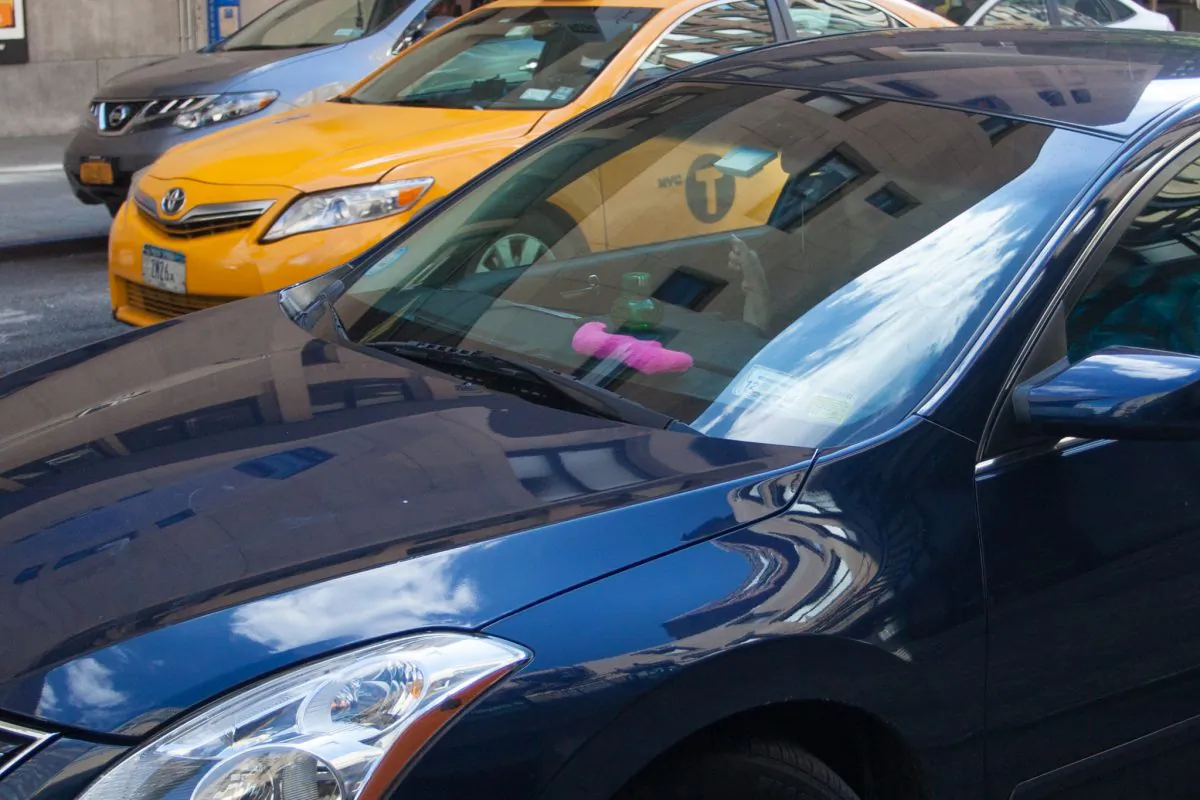 A Lyft car drives down a street with a pink mustache on its dashboard in Manhattan on Aug. 18, 2014. (Benjamin Chasteen/Epoch Times)