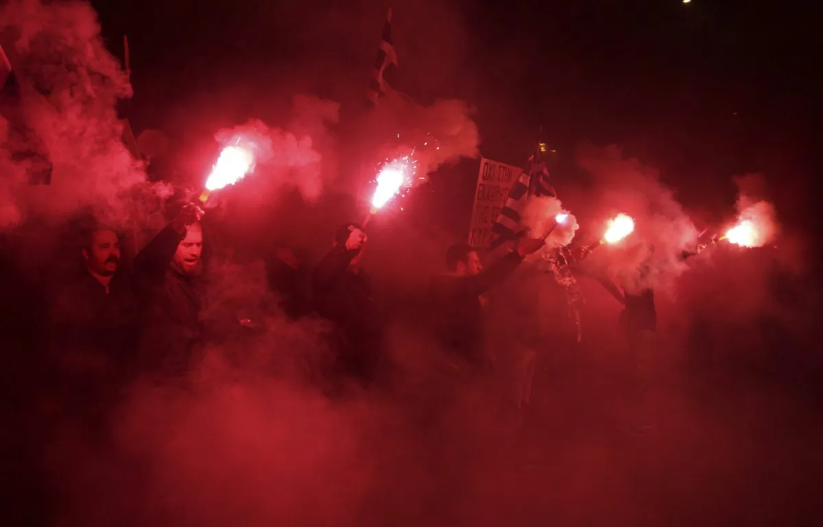 Supporters of the far-right party Golden Dawn as they sing the national anthem as they hold up flares during a protest outside the Germany embassy in Athens on March 22, 2013. A prosecutor handling the criminal investigation of Greece’s Nazi-inspired, far-right Golden Dawn party on Thursday Oct. 16, 2014  sought to have 70 party members - including the jailed party leader and 17 other lawmakers - stand trial on charges ranging from running a criminal organization to murder and weapons offences. (AP Photo/Thanassis Stavrakis)